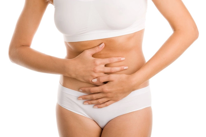 femeie care se tine de burta din cauza durerii cauzata de infectia urinara