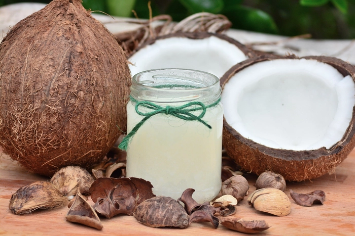 borcan de ulei de cocos prezentat alaturi de nuci de cocos