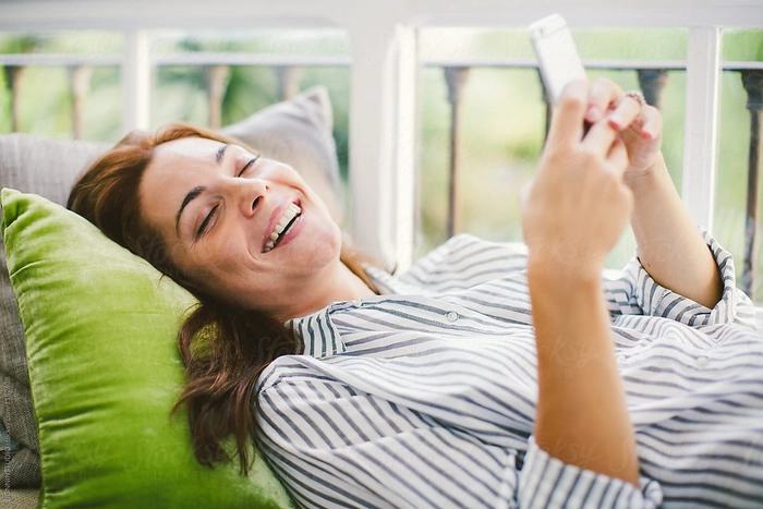 persoana care rade si se uita in telefon