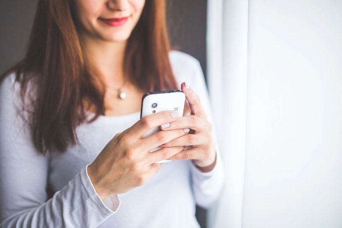 o femeie care zâmbește cu un telefon în mână