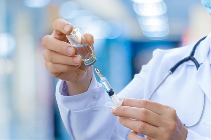 un medic care trage serul dint-o sticluta de vaccin cu seringa