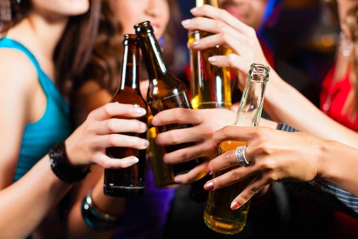 mai multe persoane ciocnesc sticle de alcool