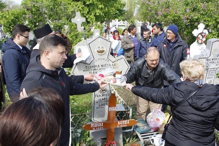  o imagine cu mai multi oameni ieseti cu pomana in cimitir