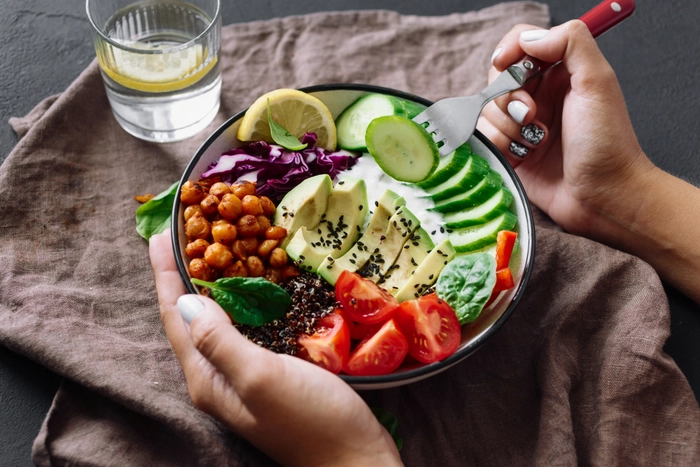 persoana care mananca o salata din alimente care nu baloneaza