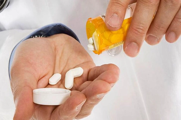 persoana care isi toarna dintr-un recipient antibiotice in mana