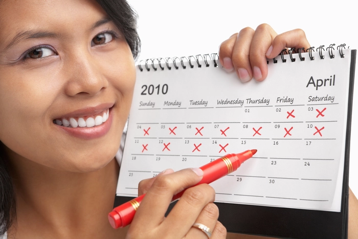 femeie care incercuieste o data in calendar zambind