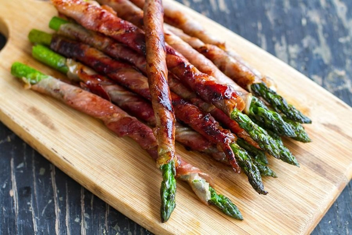 sparanghel rasucit cu bacon pe un suport de lemn