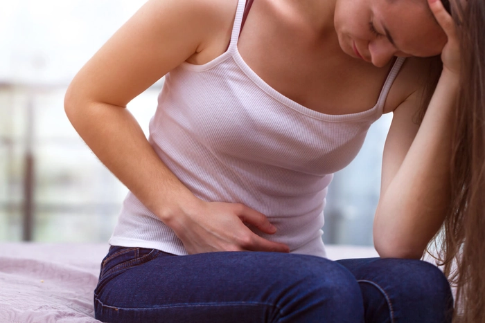 femeie care se tine de josul abdomenului din cauza durerii