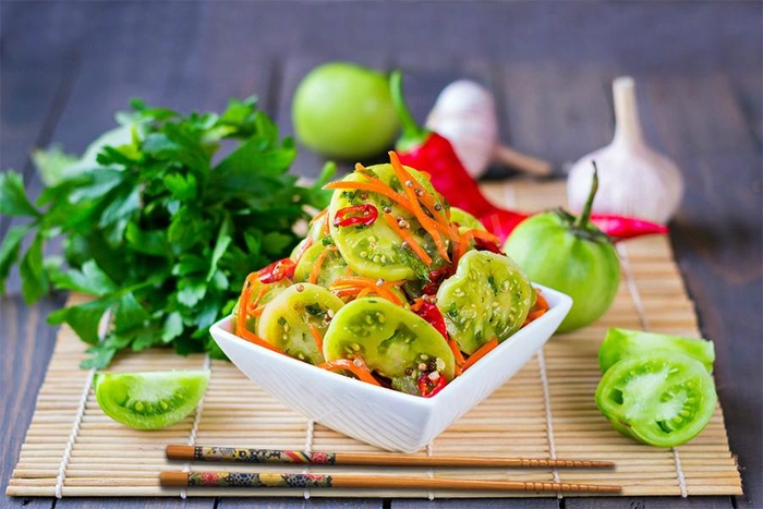 o farfurie cu salata de gogonele verzi inconjurata de mai multe ingrediente pe o masa