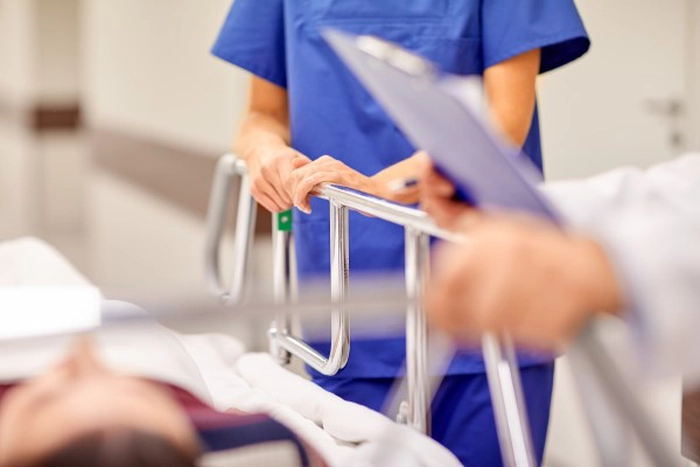 un pacient intins in pat, un doctor si o asistenta