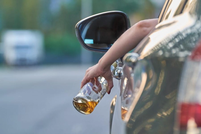 un sofer cu o sticla de alcool in mana