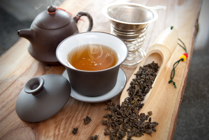 o cana de ceai detoxifiant langa un ceainic si plante din care a fost infuzat