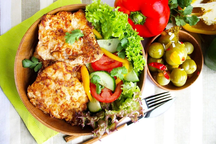 snitele de portc cu salata si masline alaturi pe o masa