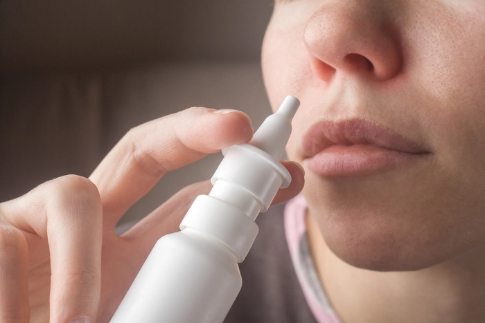 o femeie care ține în dreptul nasului un spray nazal