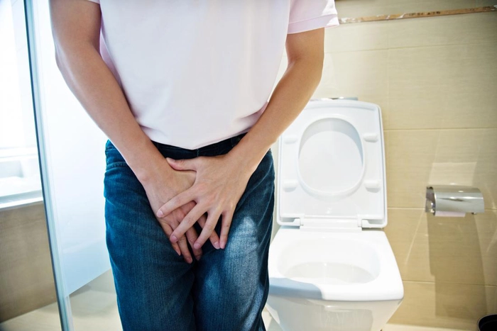 barbat care se tine de testicul din cauza urinarii greoaie intr-un viceu