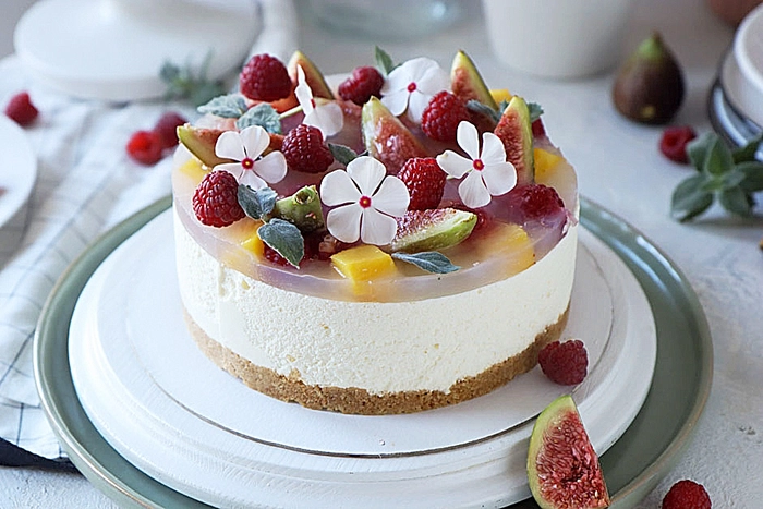 un cheesecake fara coacere cu mascarpone decorat cu fructe si flori pe o farfurie 