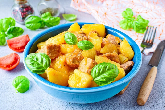 friptura cu cartofi intr-un bol pe o masa langa mai multe legume