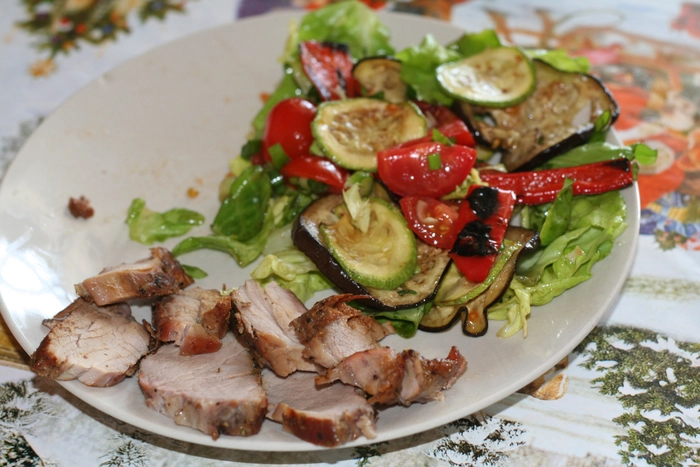 carne fripta de porc langa salata intr-o farfurie pe o masa