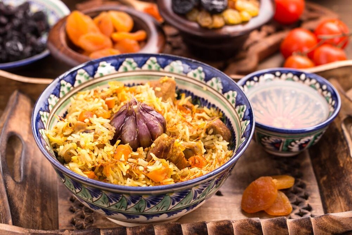 un bol cu pilaf de orez langa o cana si mai multe ingrediente pe o masa