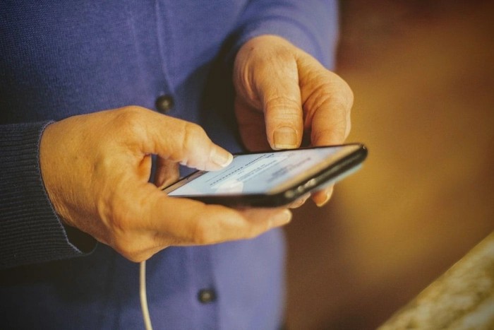o batrana cu un telefon mobil in mana