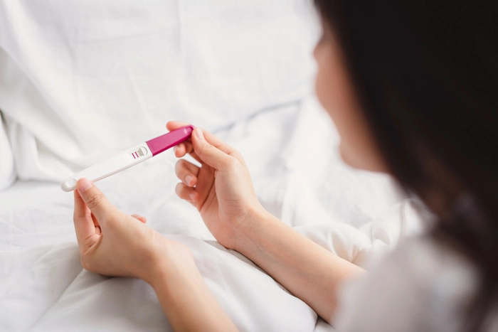 femeie care tine in mana un test de sarcina