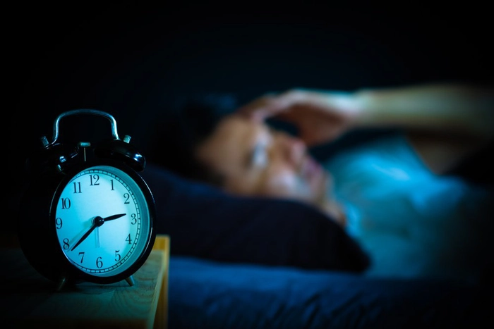 barbat care sta culcat in pat si sufera de insomnie
