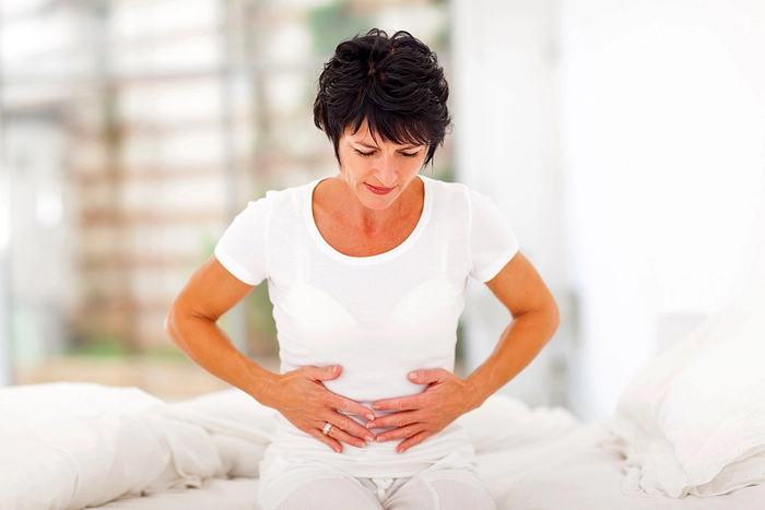 femeie care se tine cu mainele de abdomen din cauza durerii