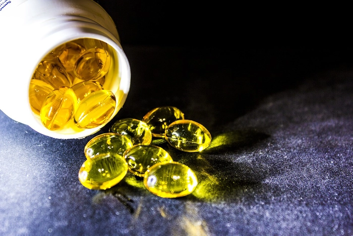 un recipient din care au cazut pe masa mai muulte capsule moi cu omega