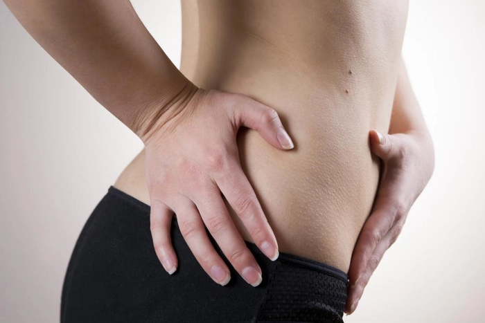 femeie care se tine de burta din cauza infectiei genitale