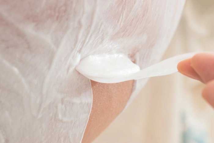 femeie care indeparteaza cu o spatula crema pentru epilare de pe picioare