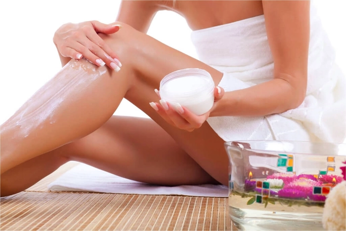 femeie care aplica o crema depilatorie pe picior