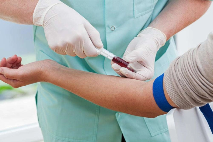 medic care preleva sange din vena unei persoane cu o seringa