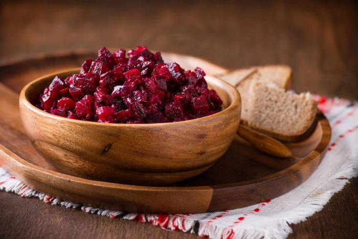 bol rustic din lemn cu salata de sfecla rosie fiarta si doua felii de paine