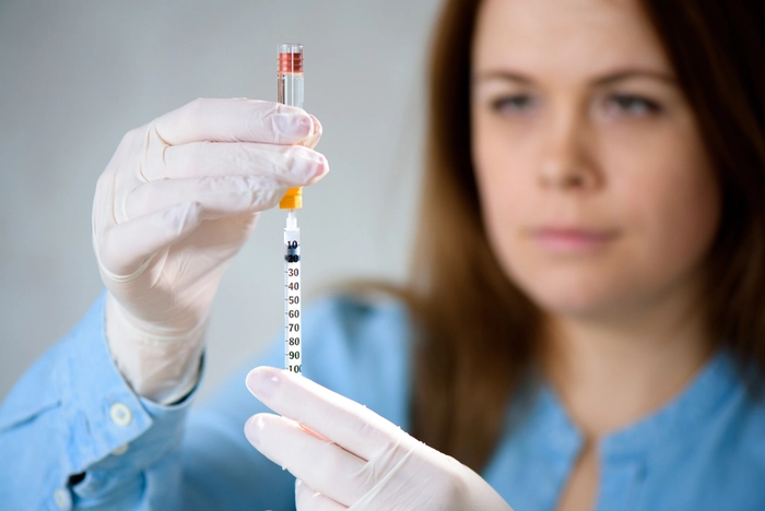 medic care priveste o siringa si o pregateste pentru a fi injectata