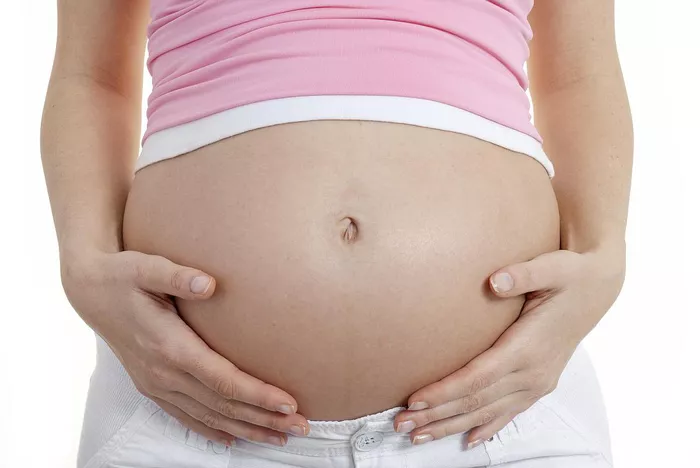femeie insarcinata care se tine de burta