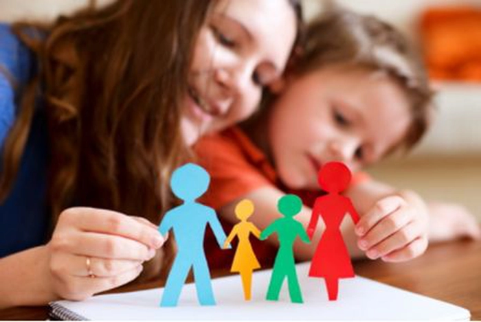 o mama cu un copil se uita la o foaie colorata decupata in forma de familie
