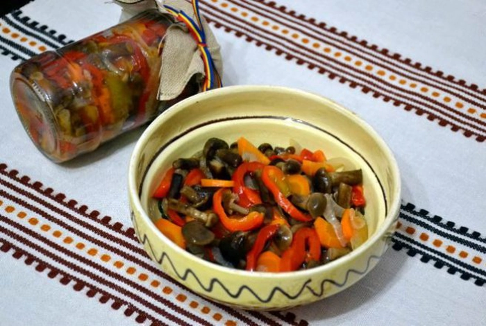 salata de bureti intr-o farfurie langa un borcan cu salata de bureti