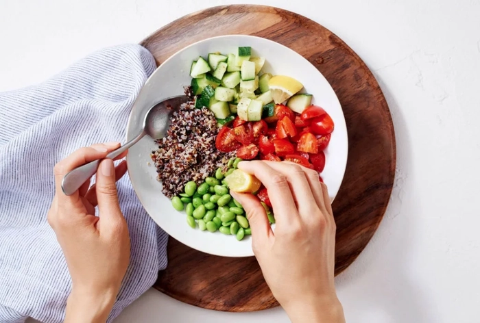 femeie care consuma o salata din legume si fasole verde