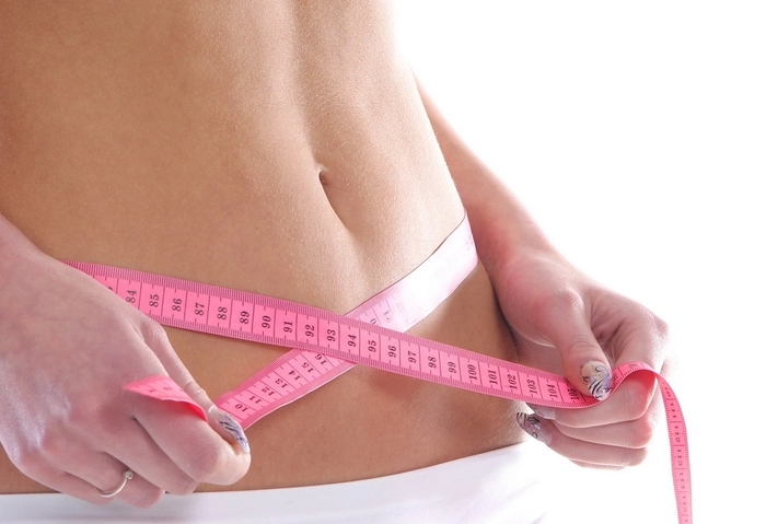 o femeie care se măsoară cu un metru roz