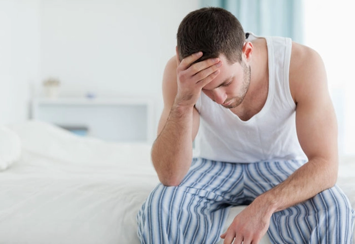 un bărbat trist îmbrăcat în maiou și pantaloni cu dungi