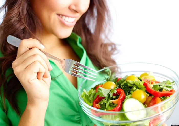 femeie care mananca o salata si zambeste