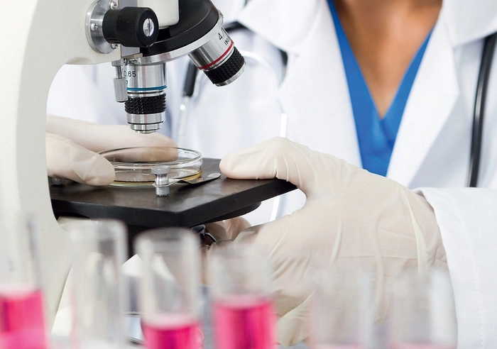 medic care analizeaza folosind un microscop o proba de sange