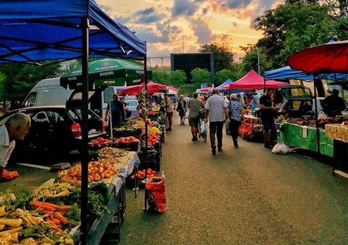 oameni in piata inconjurati de fructe si legume
