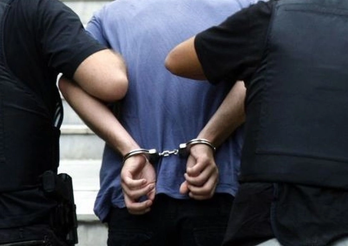 un barbat incatusat condus de catre doi politisti