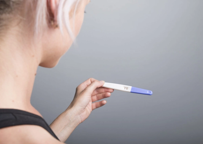 femeie care tine in mana un test pentru sarcina pozitiv