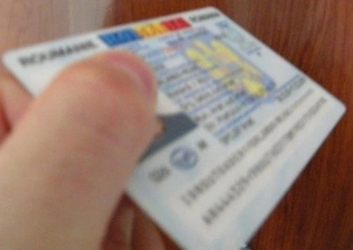 persoan[ care ține în mână o carte de identitate