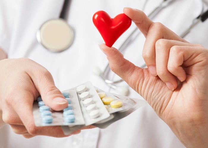 un medic cu o inimă mică în mână și cu medicamente