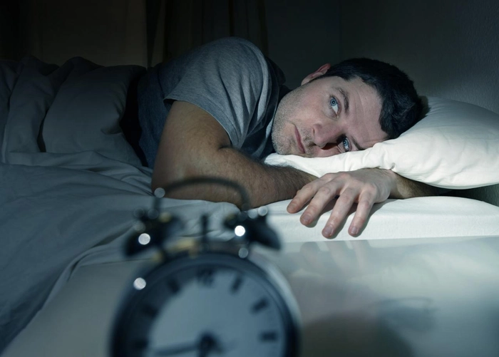 barbat care sta in pat noaptea si sufera de insomnie