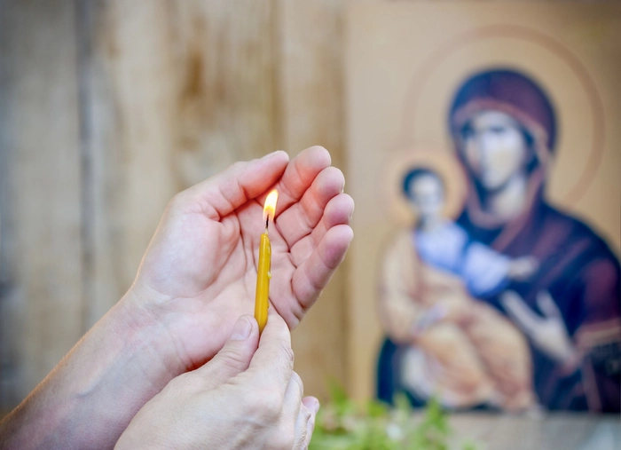 femeie care tine o lumanare in biserica