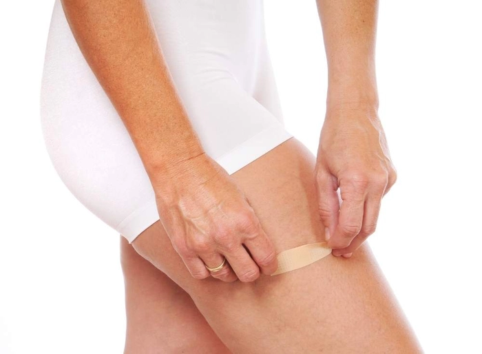 femeie care aplica un plasture pe pulpa piciorului